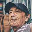 A man wearing a hat and a striped shirt is smiling.
