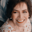 A woman is smiling and wearing a floral shirt