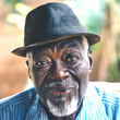 A man with a beard wearing a hat and a blue shirt