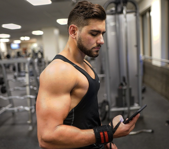 A man is looking at his phone in a gym.