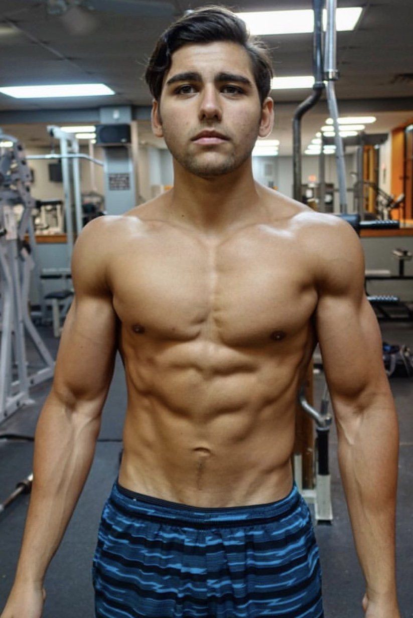 A shirtless man is standing in a gym.