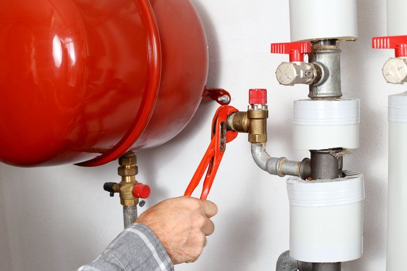 Plumber Working In A Heating Room — KNP Plumbing and Gas — Airlie Beach, QLD Plumber Working In A Heating Room — KNP Plumbing and Gas — Airlie Beach, QLD