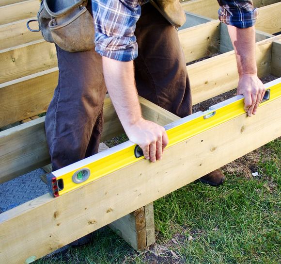 deck builder laying down level on foundation of new deck