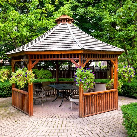 wooden gazebo surrounded by greenery in backyard