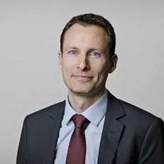 En mand i jakkesæt og slips smiler til kameraet.
