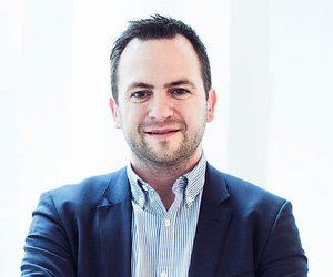 A man in a suit and striped shirt is smiling for the camera.