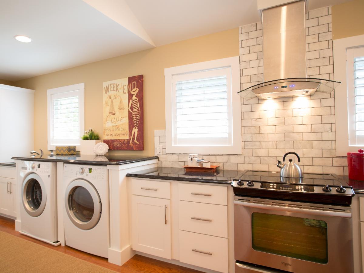 Kitchen with washer/dryer, stove, and cabinetry. White appliances, beige walls, and dark countertops.