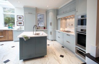 Blue and white kitchen with island, marble floors, and built-in appliances.