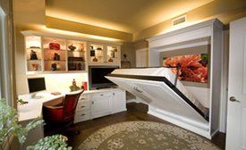 A home office with a white Murphy bed. Desk, cabinets, and built-in shelves.