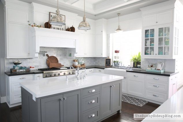 Gray and white kitchen with island, marble backsplash, and overhead lighting.