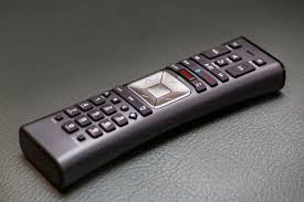 Black TV remote control on a gray surface.