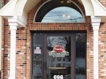 Mini house commercial insurance — in West Springfield, MA Entrance to Ormsby Insurance Agency at 698, with brickwork, arched window, and columns.