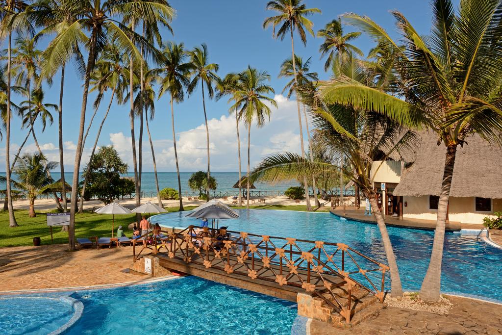 A large swimming pool surrounded by palm trees and the ocean