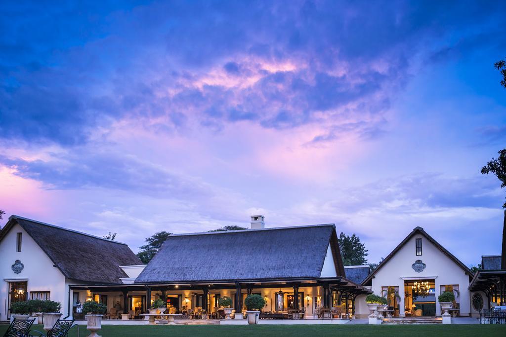 A large white house with a thatched roof is sitting on top of a lush green field.