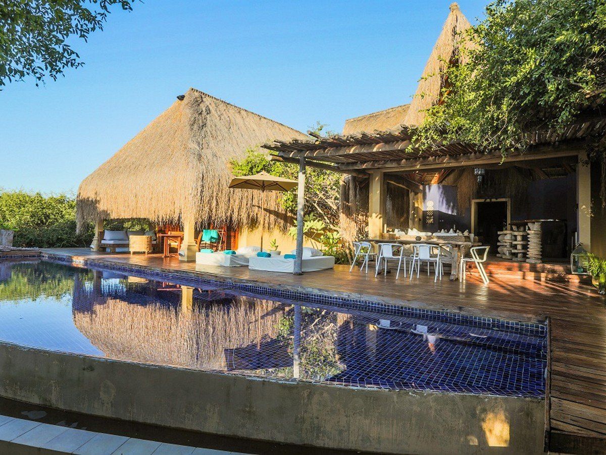 There is a large swimming pool in front of a house.