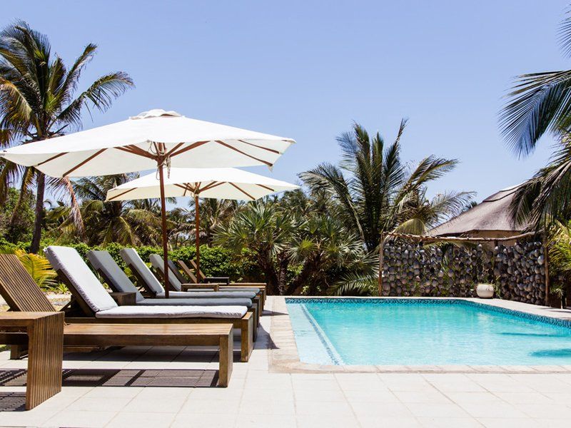 A swimming pool surrounded by chairs and umbrellas on a sunny day
