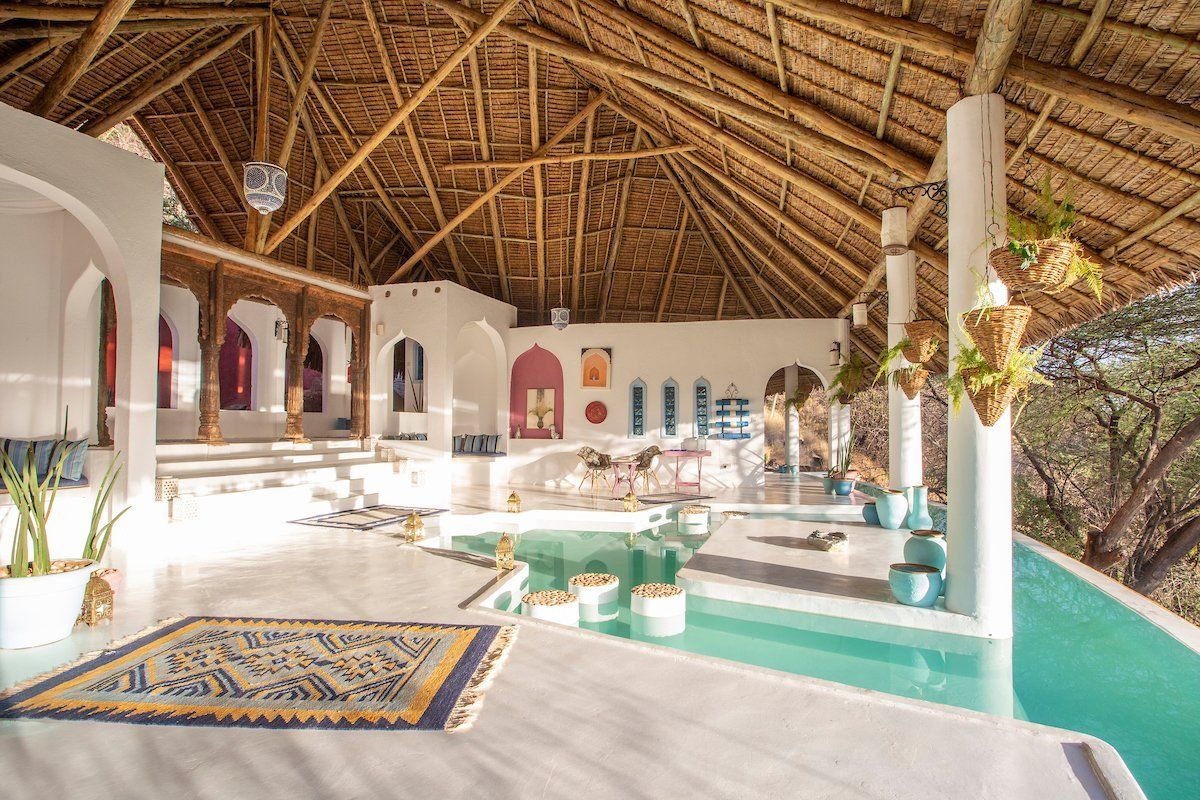 A large room with a thatched roof and a swimming pool.
