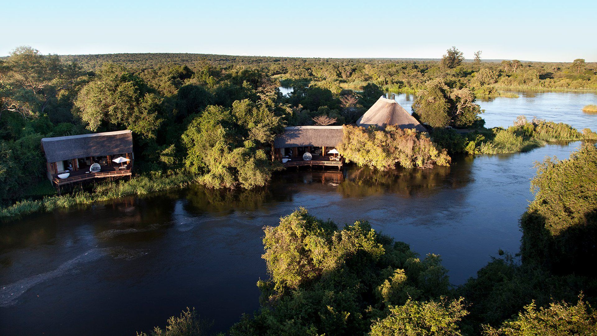 An aerial view of a house in the middle of a lake surrounded by trees.