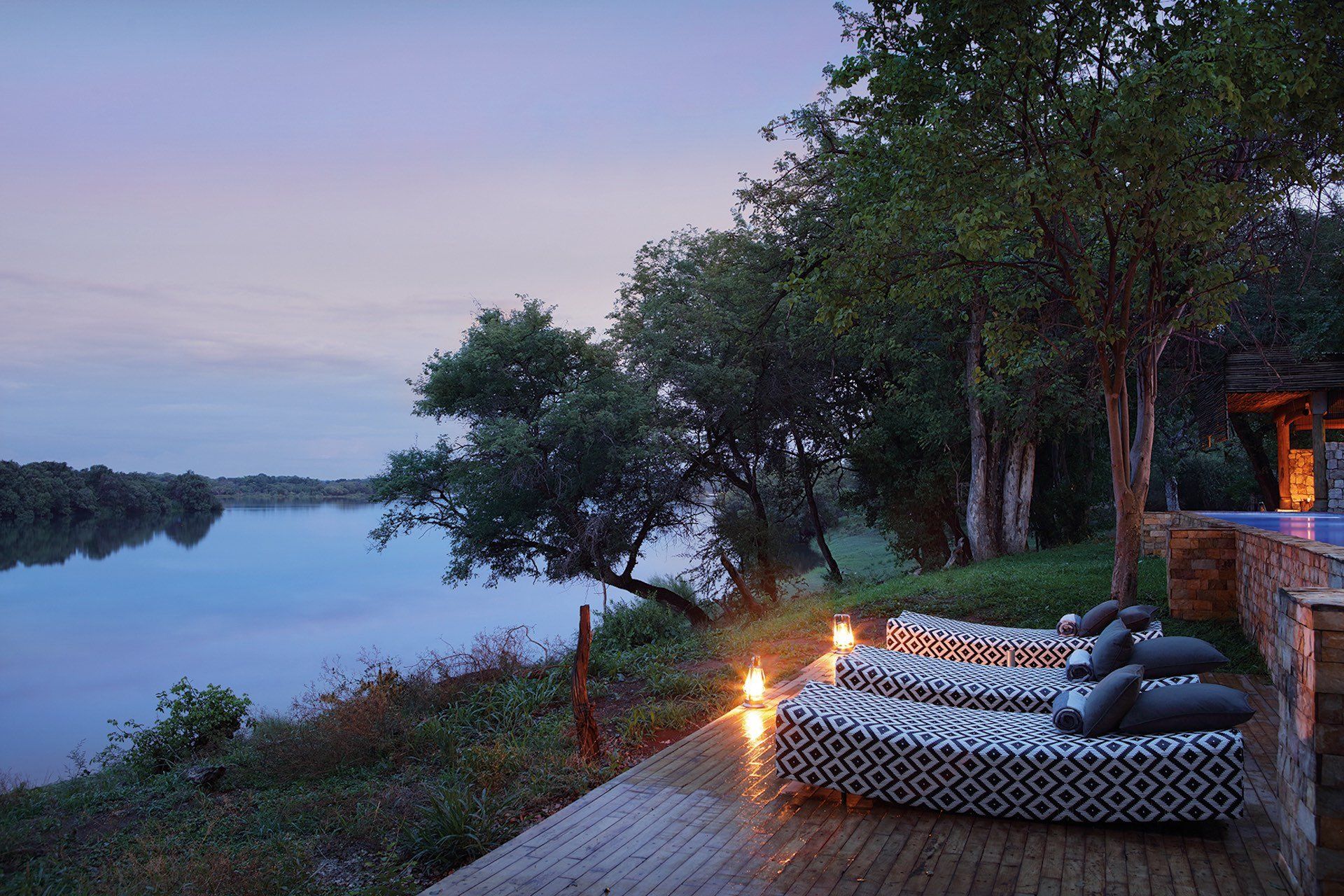 A row of lounge chairs are sitting next to a body of water.