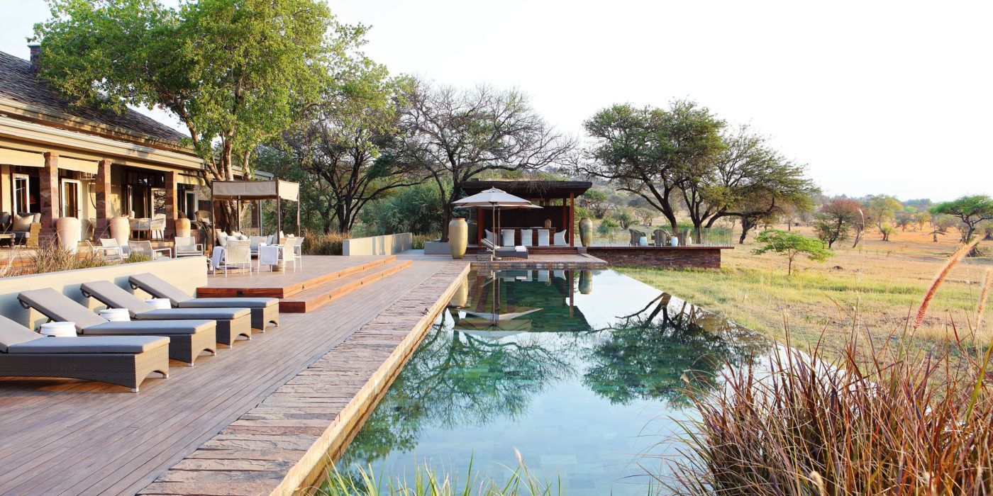 A large swimming pool is surrounded by a wooden deck and chairs.