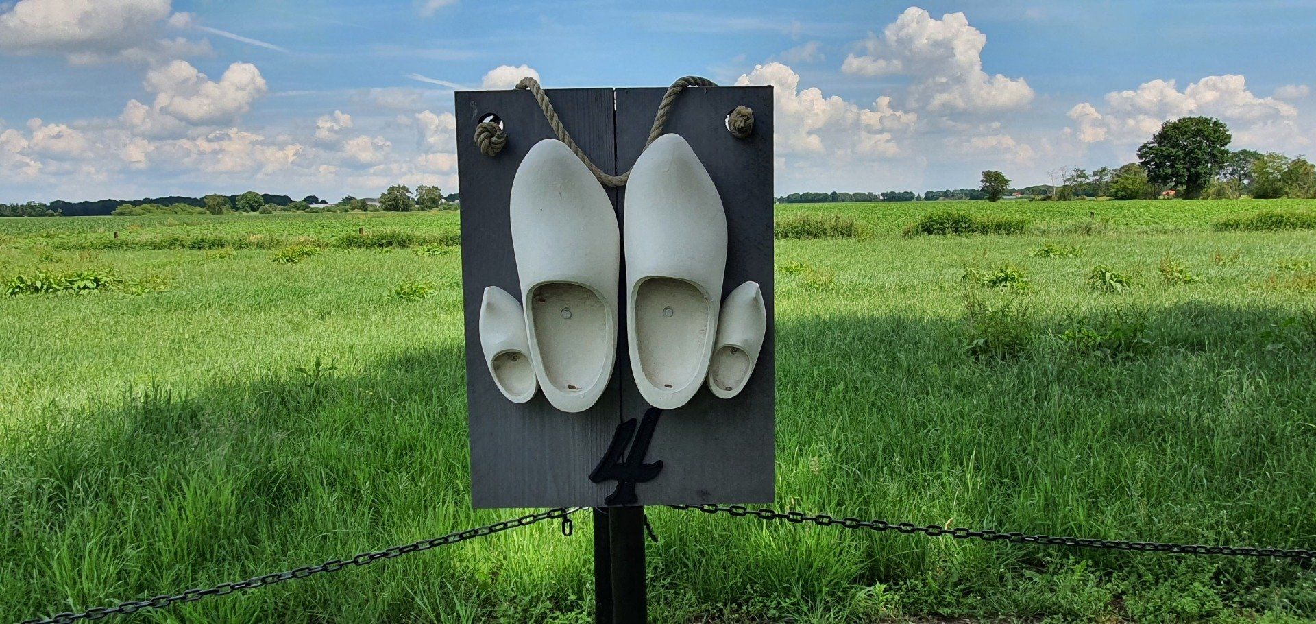Witte plastic lokvogels, gemonteerd op een paal in een groen veld onder een bewolkte hemel.