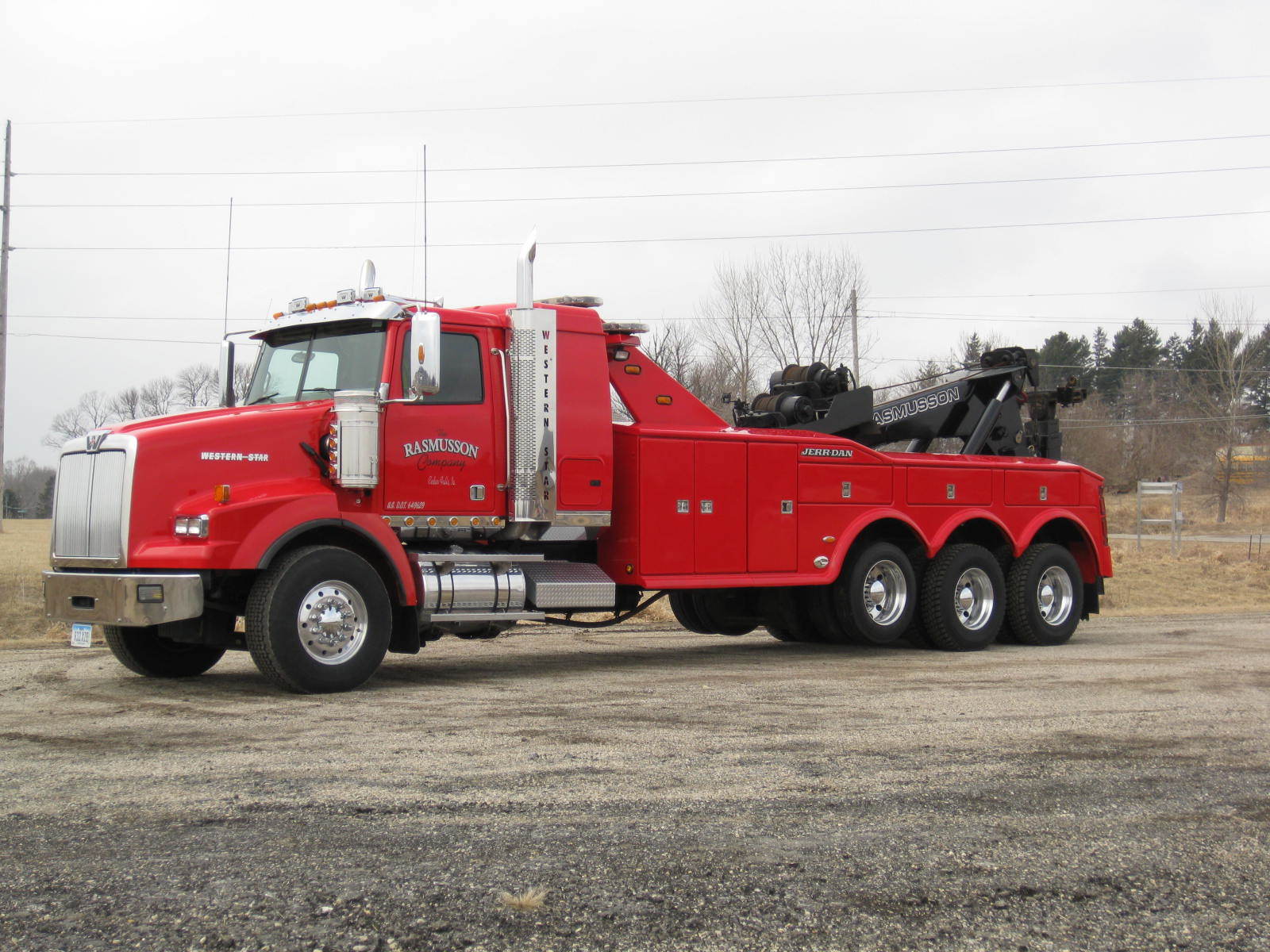 A red tow truck is parked in a gravel lot.