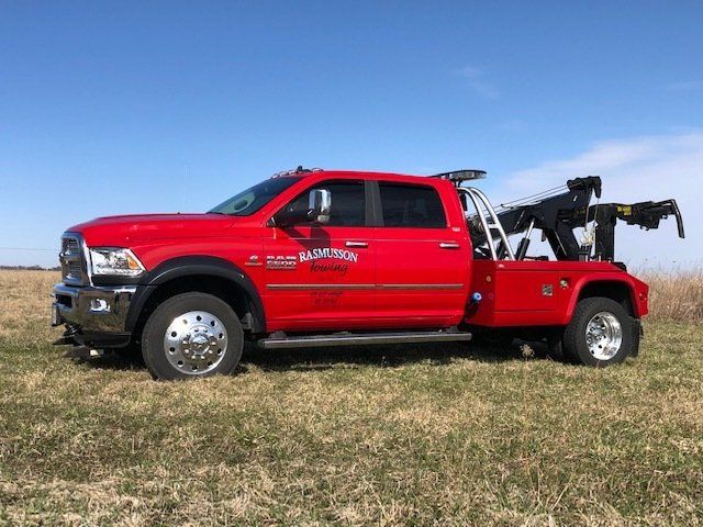 A red tow truck is parked in a grassy field.