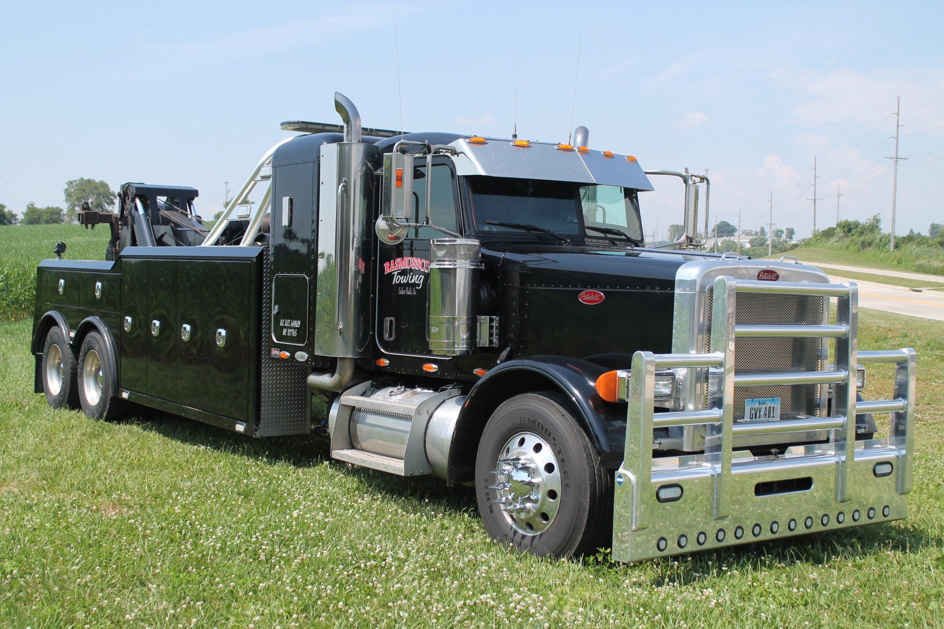 A black tow truck is parked in a grassy field