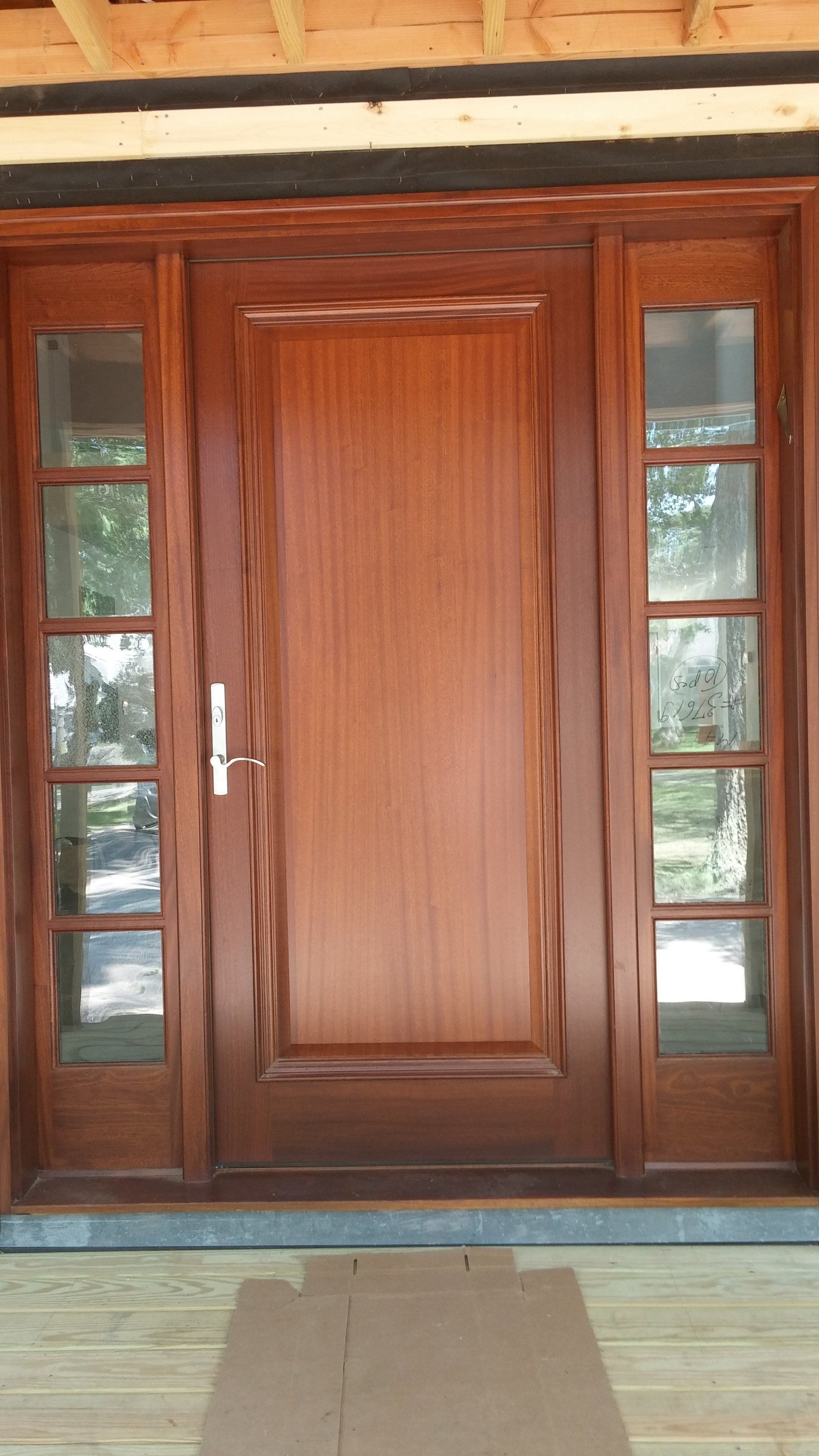 A wooden door with sliding glass doors is sitting on a wooden porch.