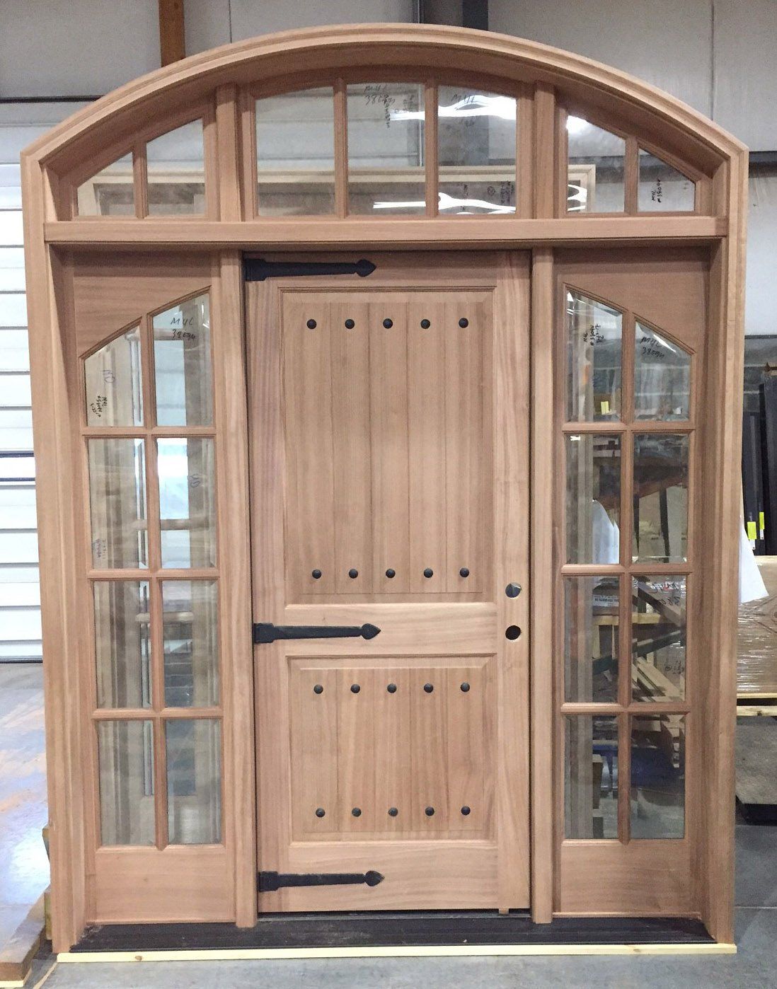 A wooden door with arched windows and a black hinge