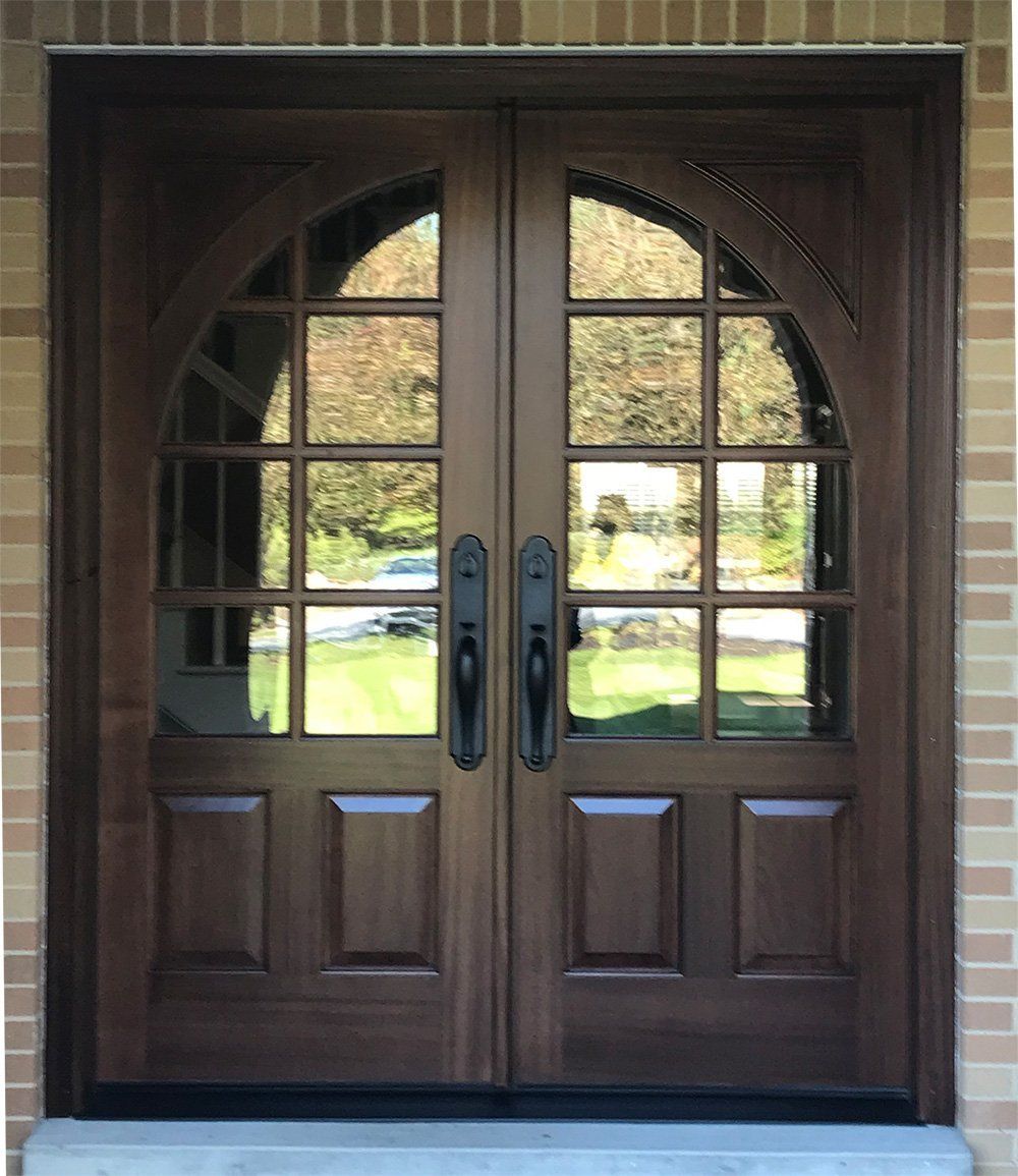 A wooden door with arched windows on a brick building