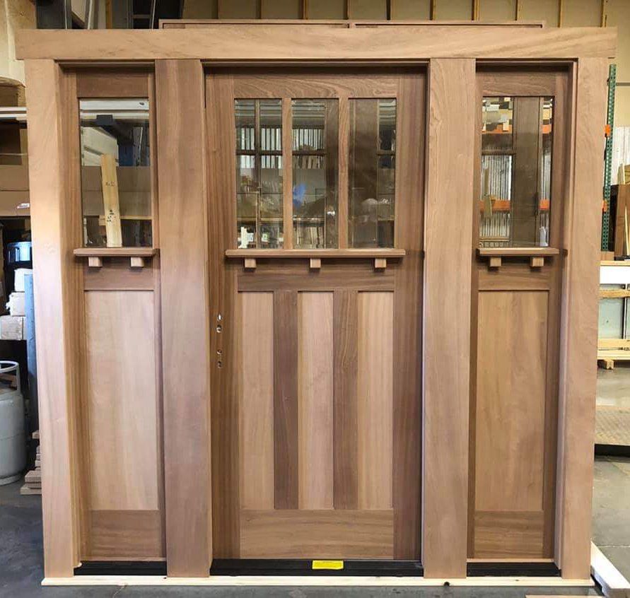 A wooden door with three windows is sitting on a table in a room.