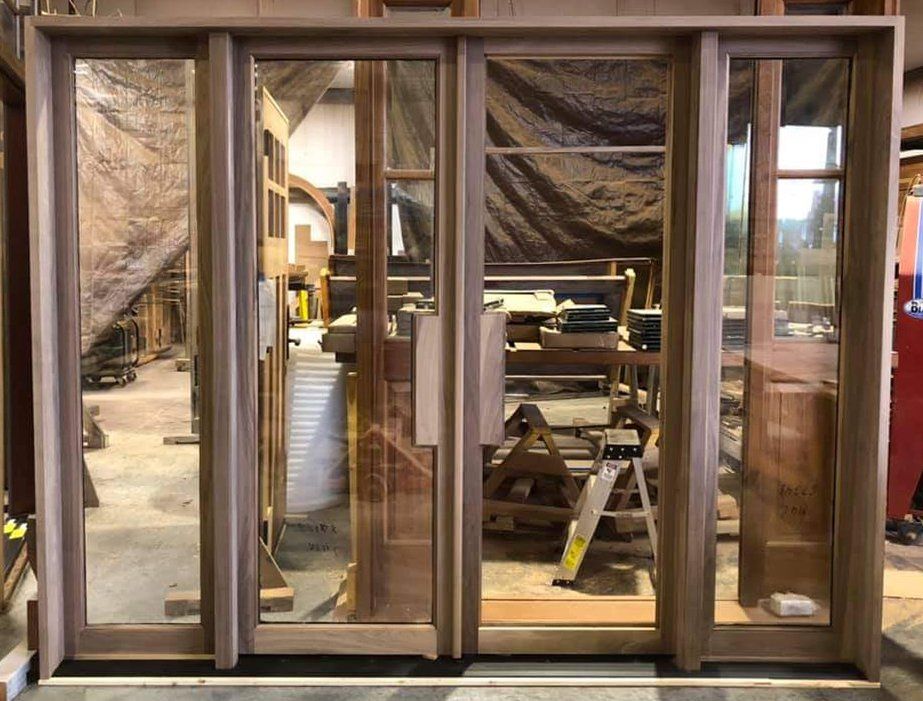 A large wooden door is sitting in a room with a lot of windows.