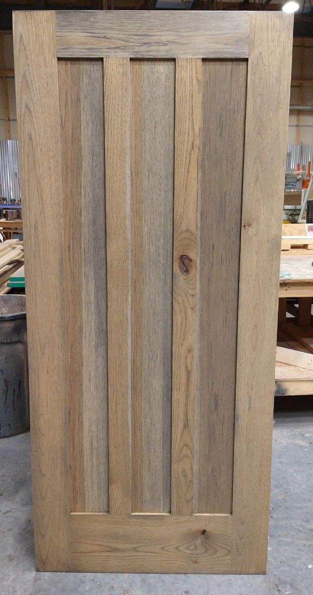 A wooden door is sitting on a concrete floor in a workshop.