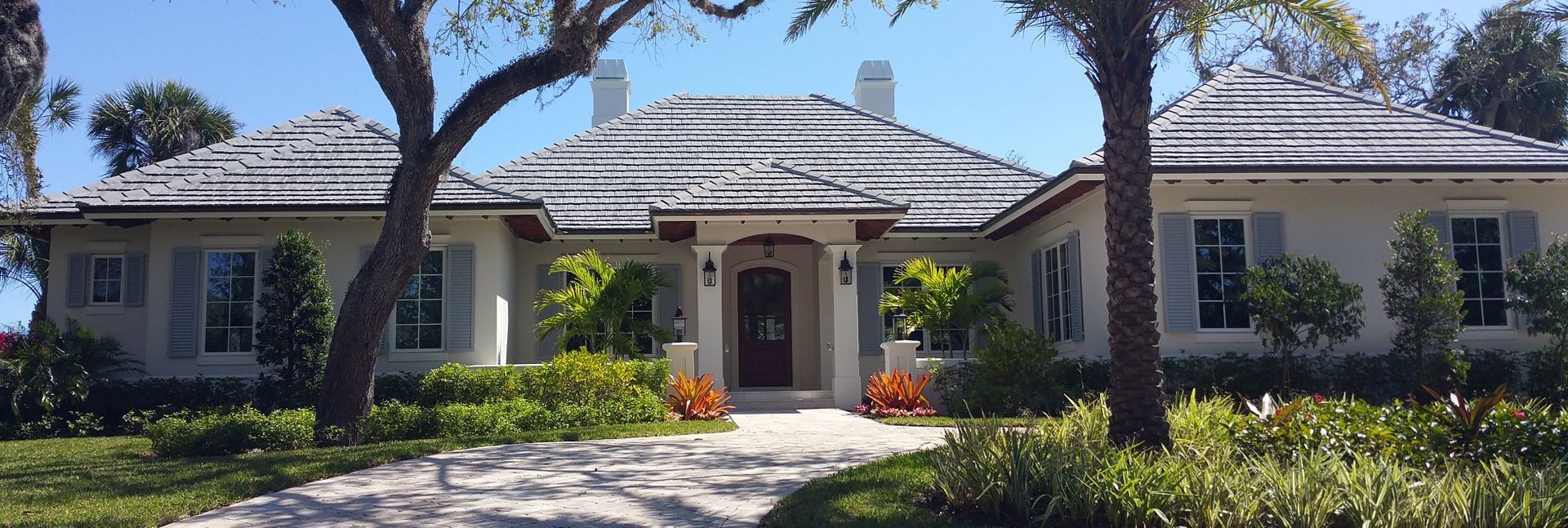 A large white house with a thatched roof and palm trees in front of it.