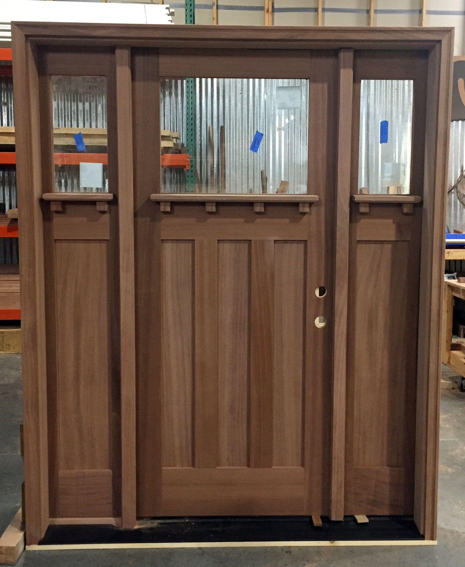 A wooden door with three windows is in a warehouse