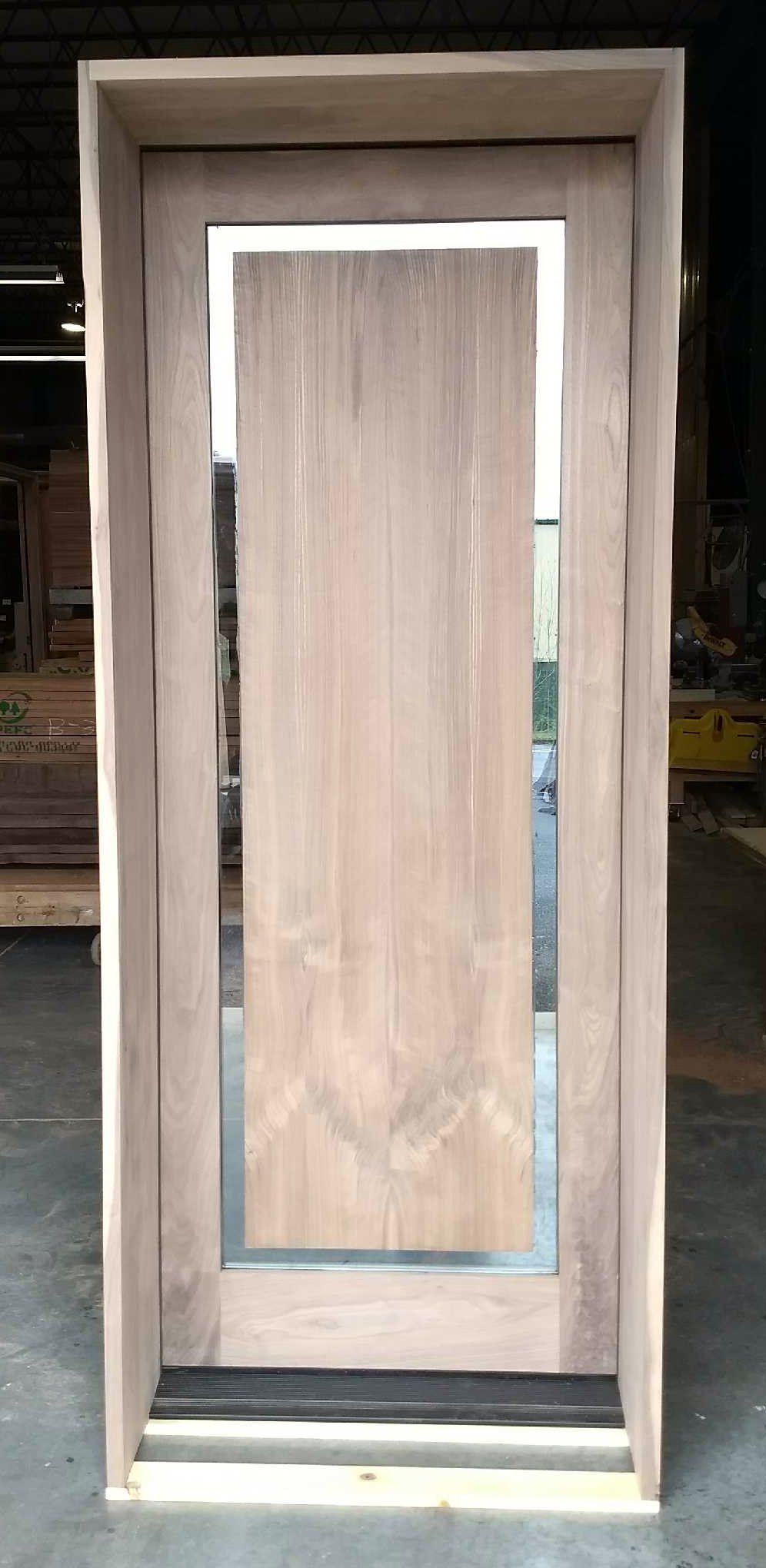 A wooden door with a mirror on the side is sitting in a warehouse.