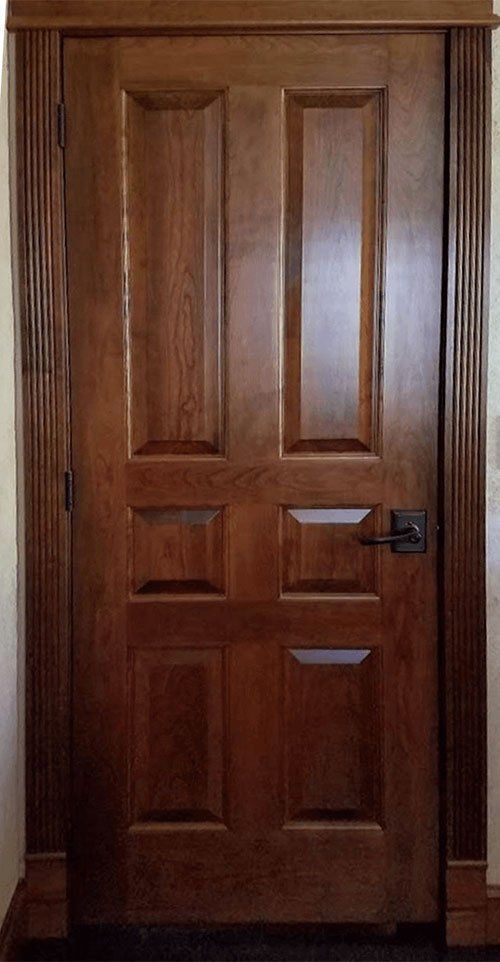 A close up of a wooden door with a black handle.
