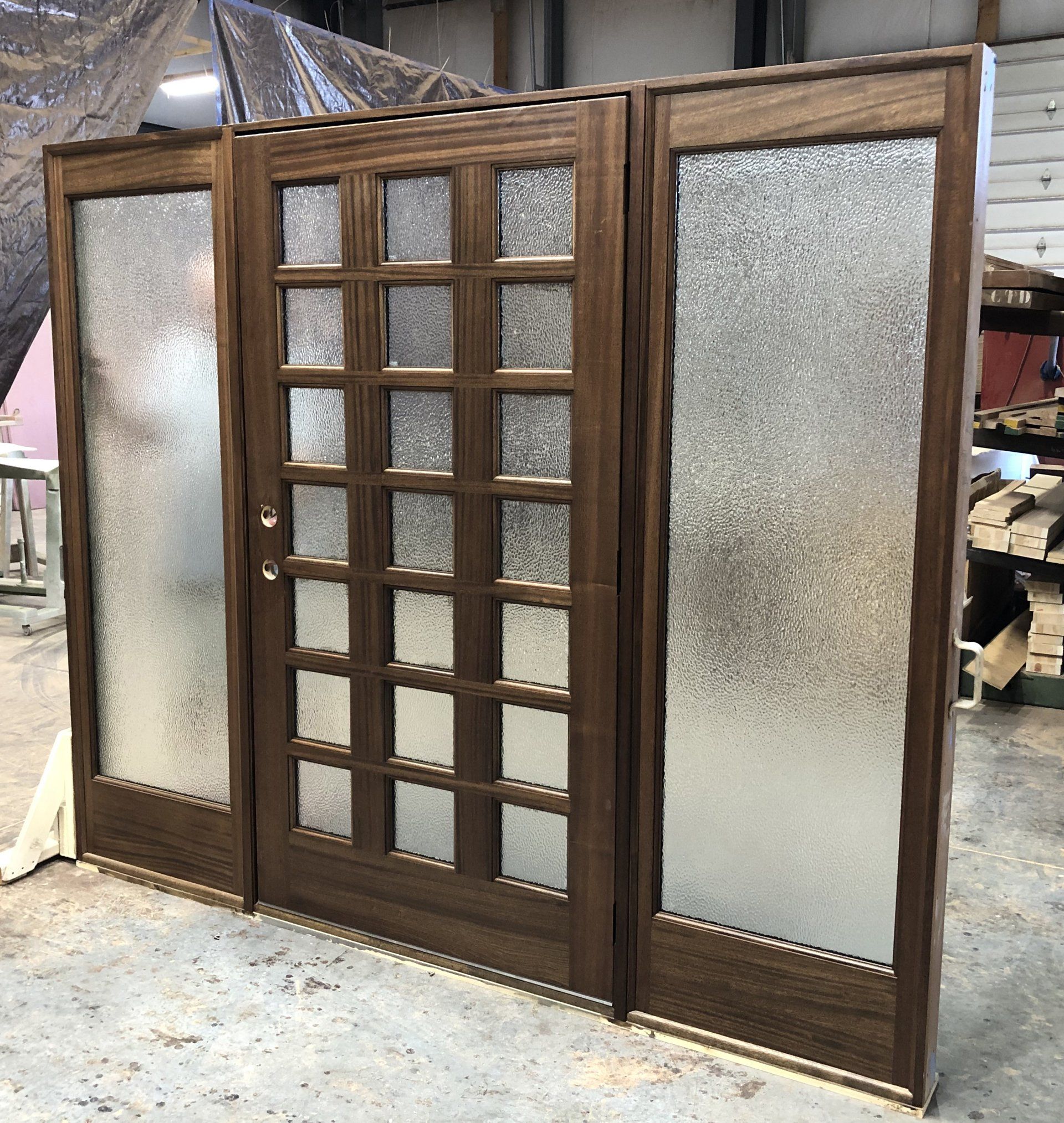 A wooden door with frosted glass is sitting on a concrete floor