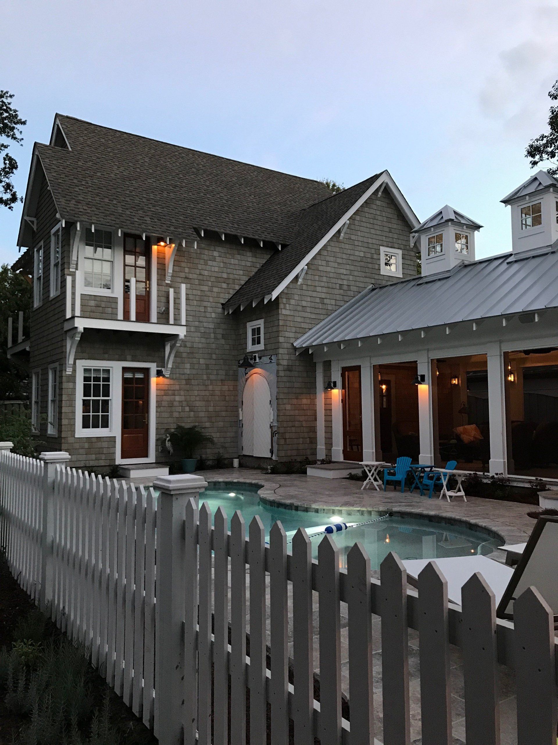 A house with a pool and a white picket fence