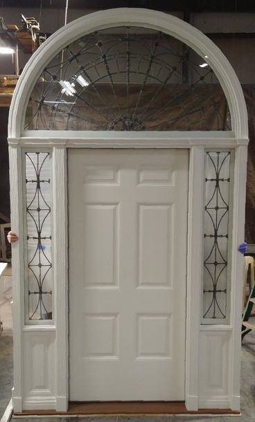 A white door with a stained glass window is sitting in a room.