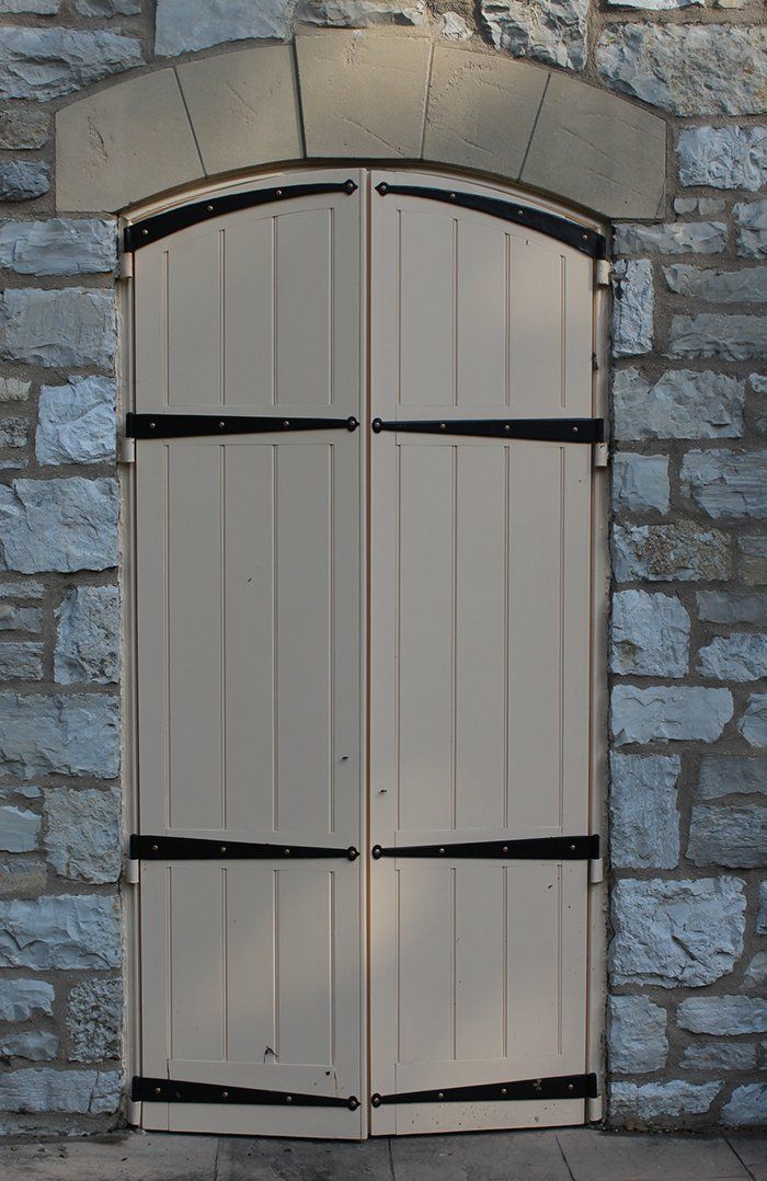 A white door with black straps on a stone wall