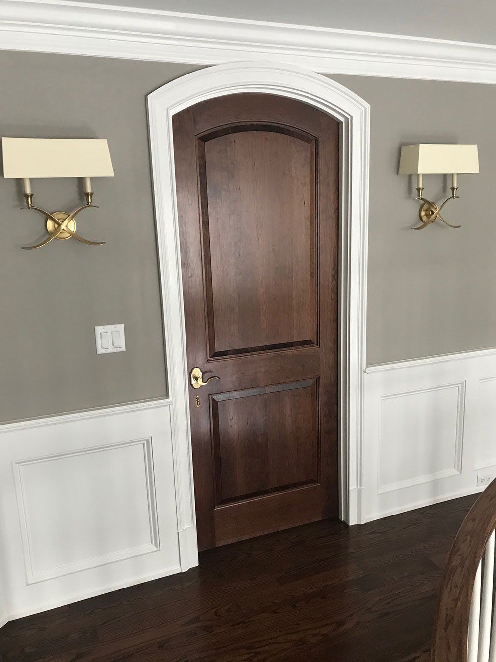 A dining room with a wooden door and two lamps on the wall.