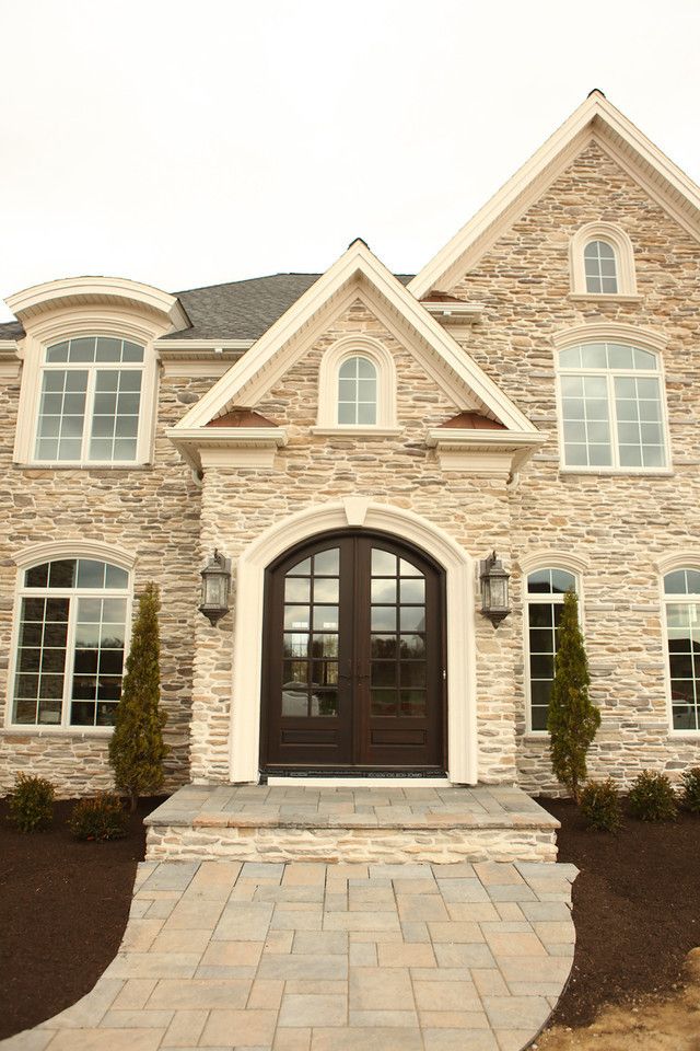 A large stone house with a walkway leading to the front door