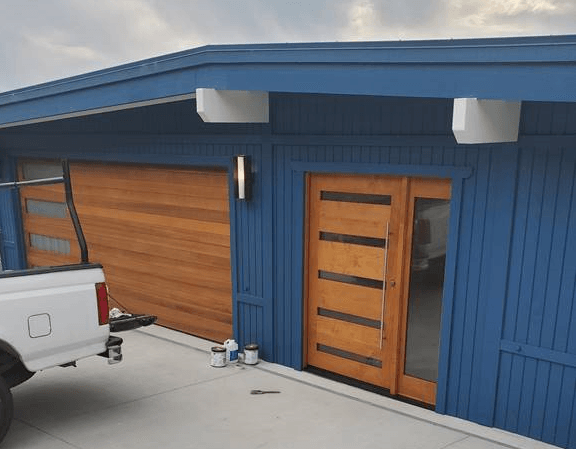 A white truck is parked in front of a blue house