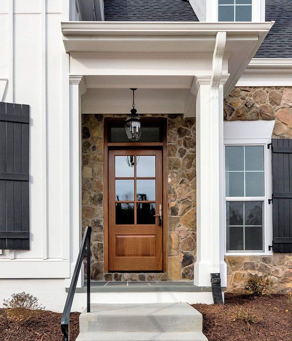 A white house with a wooden door and black shutters