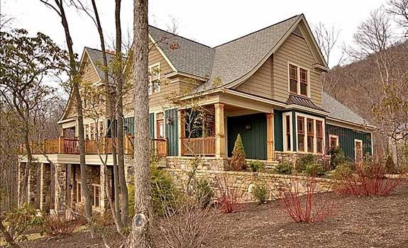 A large house with a large porch is surrounded by trees.