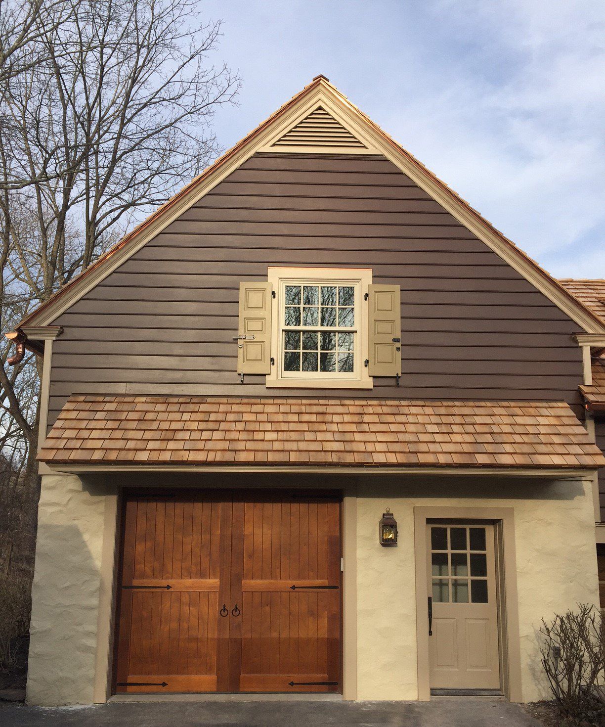 A brown house with a wooden garage door and a window