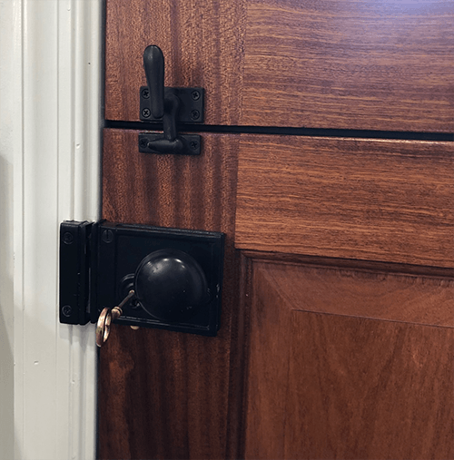 A wooden door with a black latch and a key