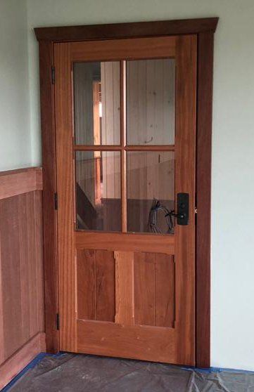 A wooden door with a glass window in a room.